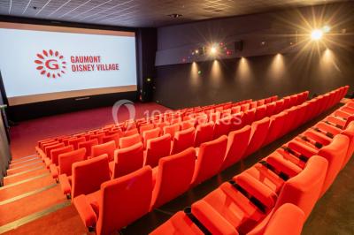 Miniature Location salle Champs-sur-Marne (Seine-et-Marne) - Pathé Disney Village #1 Salle de cinéma vide avec des rangées de sièges rouges, éclairage tamisé et écran en fond.