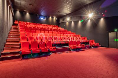 Miniature Location salle Champs-sur-Marne (Seine-et-Marne) - Pathé Disney Village #12 Salle de cinéma vide avec des rangées de sièges rouges, éclairage tamisé et écran en fond.