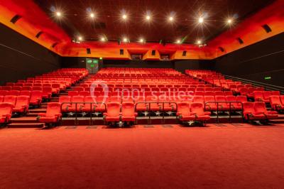 Miniature Location salle Champs-sur-Marne (Seine-et-Marne) - Pathé Disney Village #16 Salle de cinéma vide avec des rangées de sièges rouges, éclairage tamisé et écran en fond.