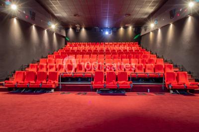 Miniature Location salle Champs-sur-Marne (Seine-et-Marne) - Pathé Disney Village #22 Salle de cinéma vide avec des rangées de sièges rouges, éclairage tamisé et écran en fond.