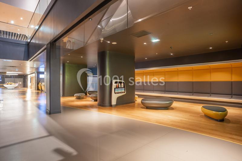 Espace intérieur moderne avec bancs arrondis, murs jaunes et éclairage tamisé.