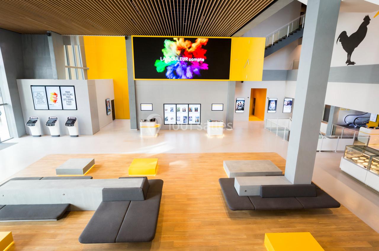 Vue intérieure d'un espace moderne avec des sièges, un écran géant coloré et des bornes interactives.