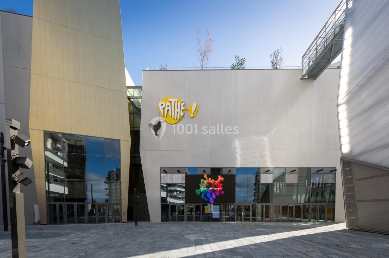 Façade d'un cinéma moderne avec logo Pathé, écran numérique coloré et architecture contemporaine.