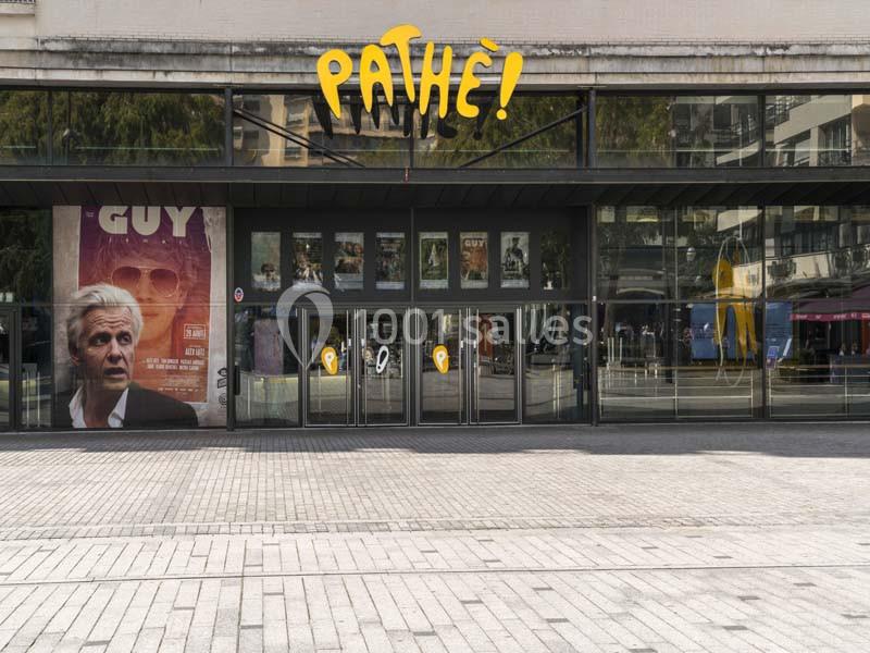 Location salle Boulogne-Billancourt (Hauts-de-Seine) - Pathé Boulogne #2 Façade d'un cinéma Pathé avec affiches de films et entrée vitrée donnant sur une place pavée.