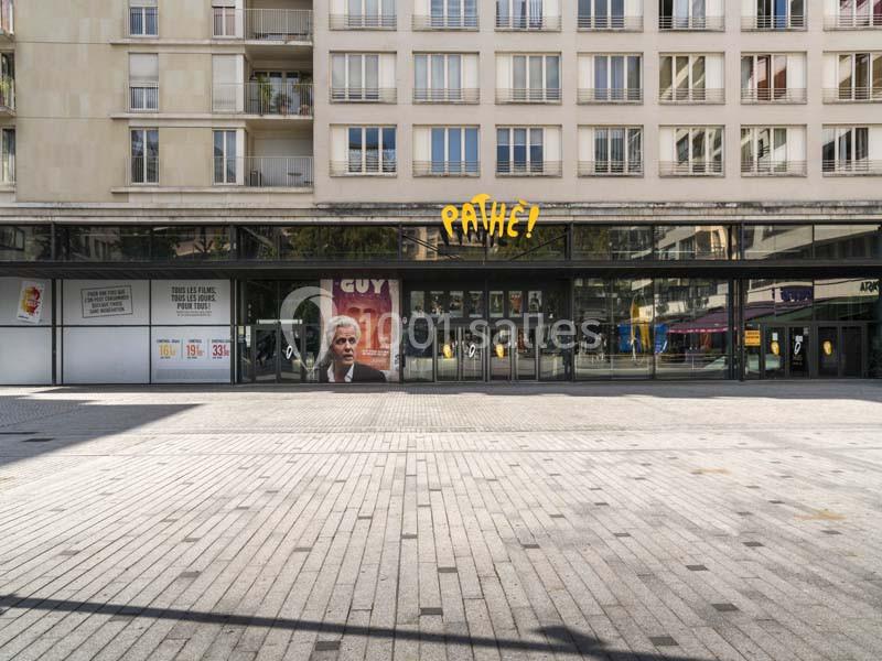 Location salle Boulogne-Billancourt (Hauts-de-Seine) - Pathé Boulogne #21 Façade d'un cinéma Pathé avec une affiche de film visible, située devant une place pavée.