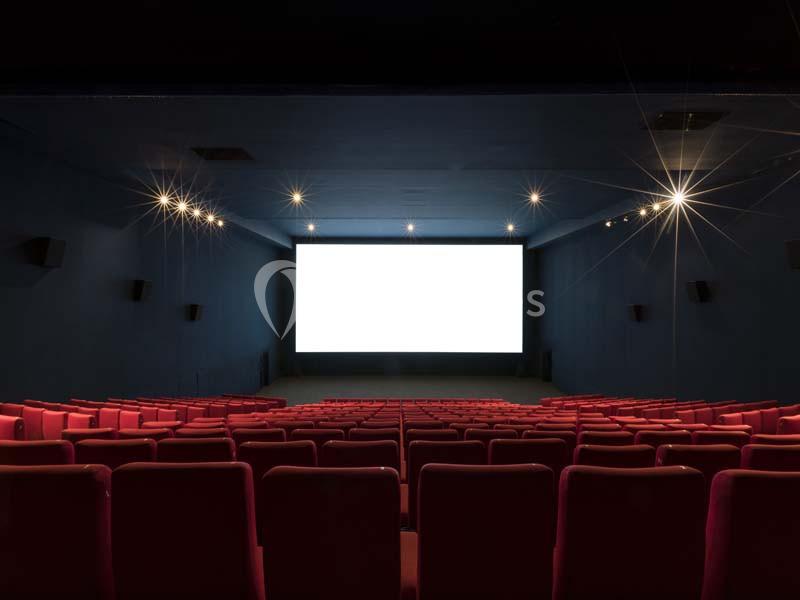 Location salle Boulogne-Billancourt (Hauts-de-Seine) - Pathé Boulogne #15 Salle de cinéma vide avec des rangées de sièges rouges et un écran blanc allumé au fond.