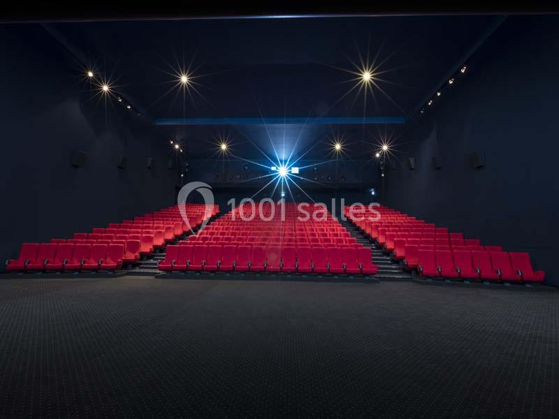 Location salle Boulogne-Billancourt (Hauts-de-Seine) - Pathé Boulogne #23 Salle de cinéma vide avec des rangées de sièges rouges et un projecteur allumé au fond.