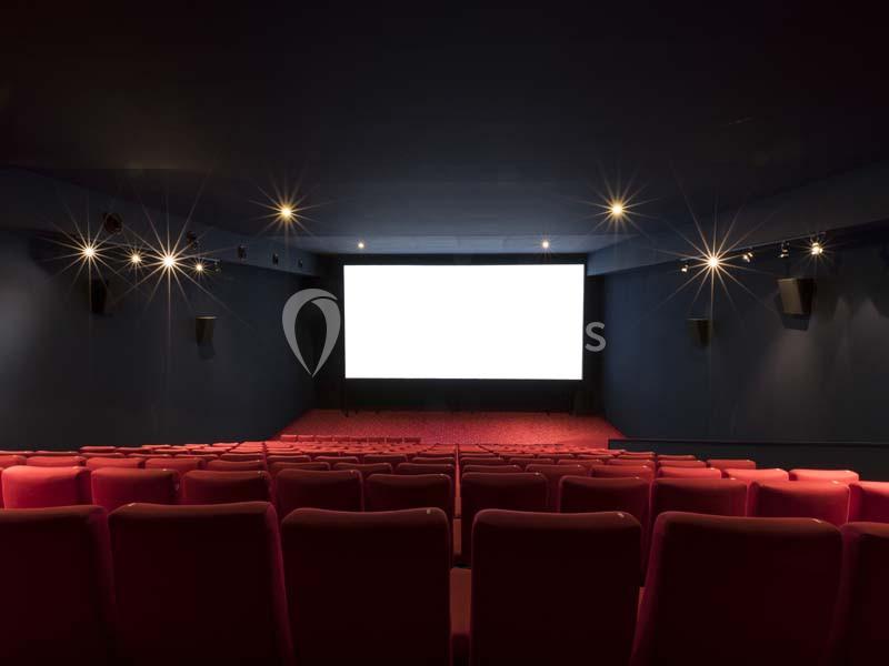 Location salle Boulogne-Billancourt (Hauts-de-Seine) - Pathé Boulogne #22 Salle de cinéma vide avec rangées de sièges rouges et un grand écran blanc allumé au fond.