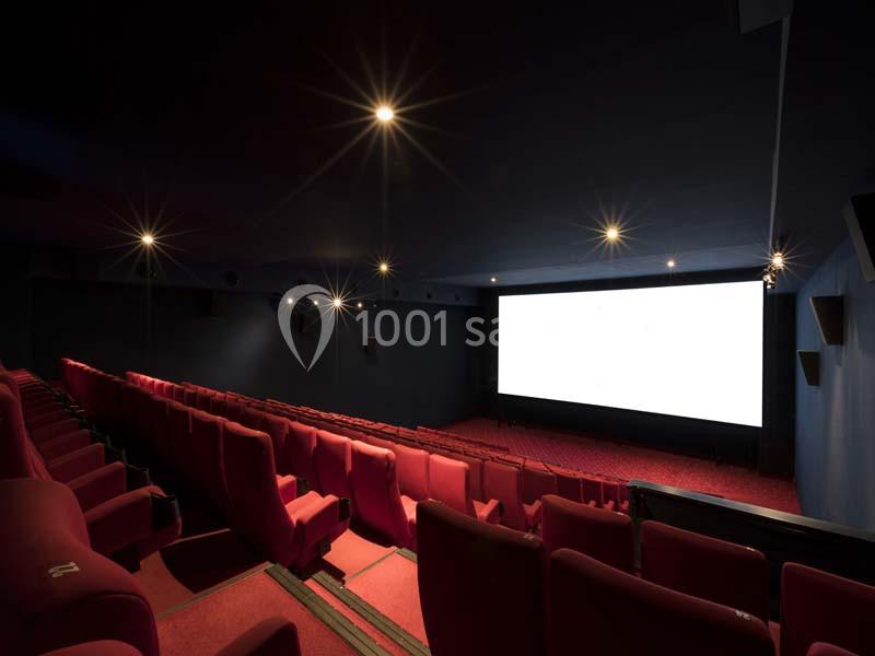 Location salle Boulogne-Billancourt (Hauts-de-Seine) - Pathé Boulogne #18 Salle de cinéma vide avec des rangées de sièges rouges et un écran blanc allumé au fond.