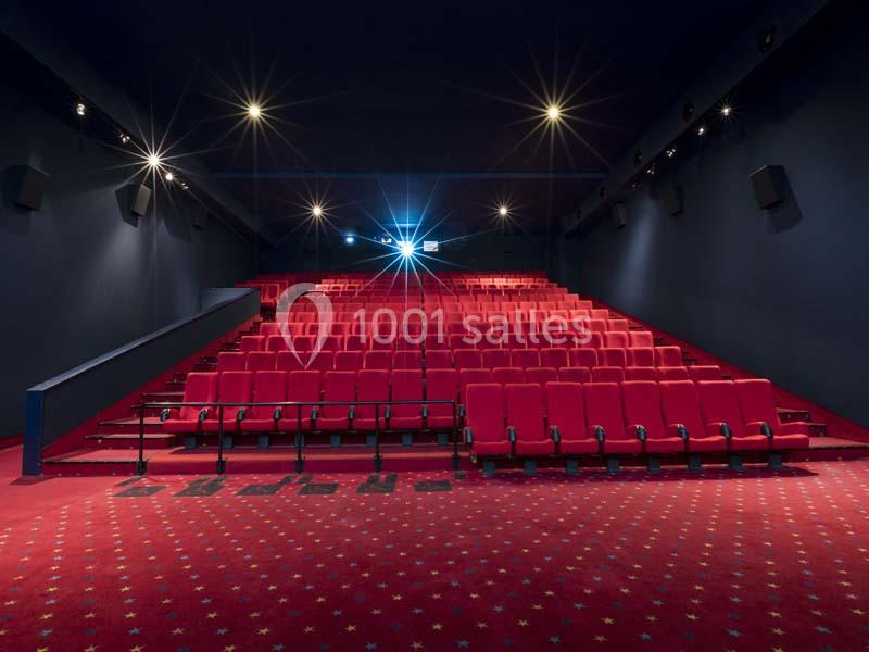 Location salle Boulogne-Billancourt (Hauts-de-Seine) - Pathé Boulogne #5 Salle de cinéma vide avec des rangées de sièges rouges et un écran allumé au fond.
