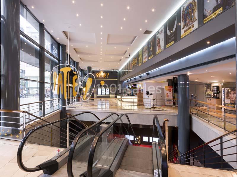Location salle Boulogne-Billancourt (Hauts-de-Seine) - Pathé Boulogne #13 Intérieur d'un cinéma avec escalators, affiches de films sur les murs et guichet visible au fond.