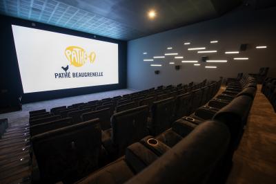 Salle de cinéma vide avec des rangées de sièges rouges et un éclairage tamisé sur les murs.