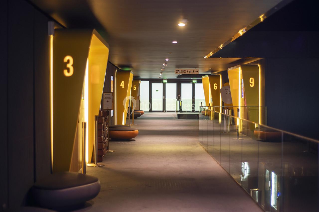 Couloir moderne avec éclairage tamisé, numéros lumineux sur les alcôves et portes vitrées au fond.