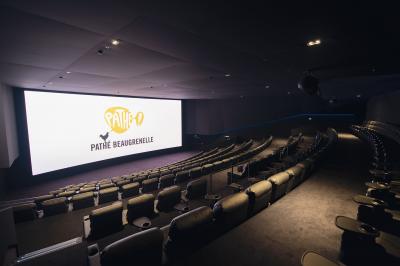 Salle de cinéma vide avec des rangées de sièges rouges et un éclairage tamisé sur les murs.