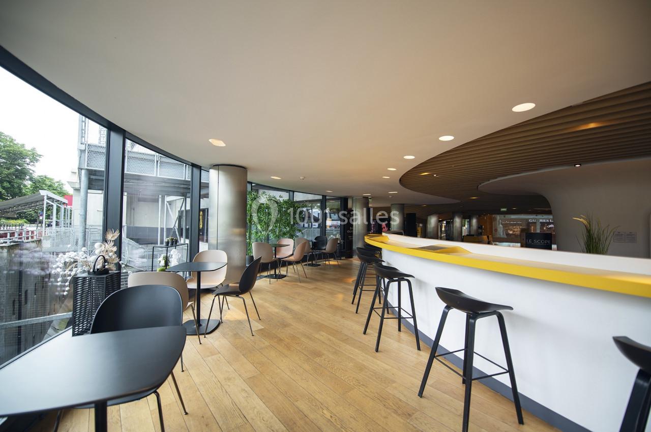 Espace intérieur lumineux avec comptoir incurvé, chaises modernes et grandes baies vitrées donnant sur l'extérieur.