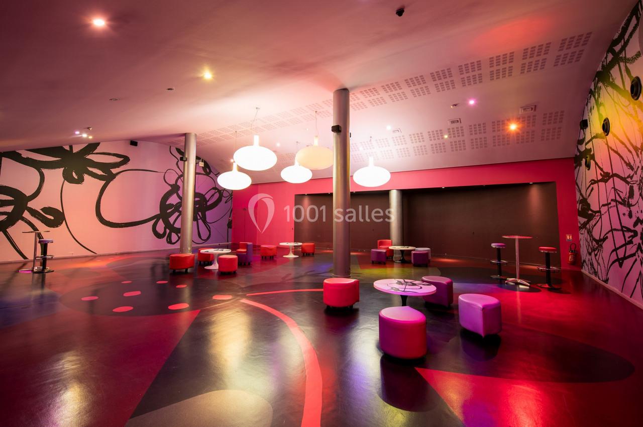 Location salle Paris 15 (Paris) - Pathé Aquaboulevard #5 Salle moderne avec murs décorés de motifs floraux, éclairage coloré et mobilier bas, composée de poufs et tables.