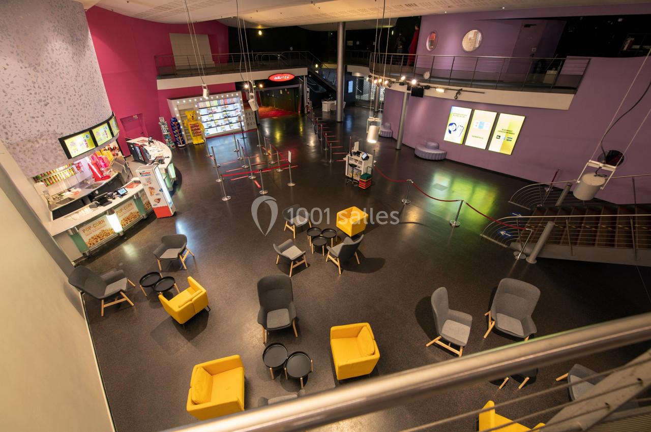 Location salle Paris 15 (Paris) - Pathé Aquaboulevard #10 Vue d'un espace d'accueil moderne avec fauteuils colorés, comptoir de confiserie et escalier menant à un étage.