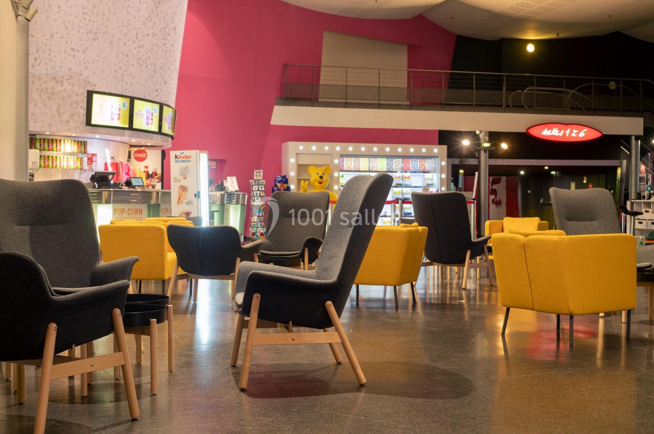 Location salle Paris 15 (Paris) - Pathé Aquaboulevard #13 Espace détente avec fauteuils colorés et tables basses dans un hall lumineux, près d'un comptoir de snacks.