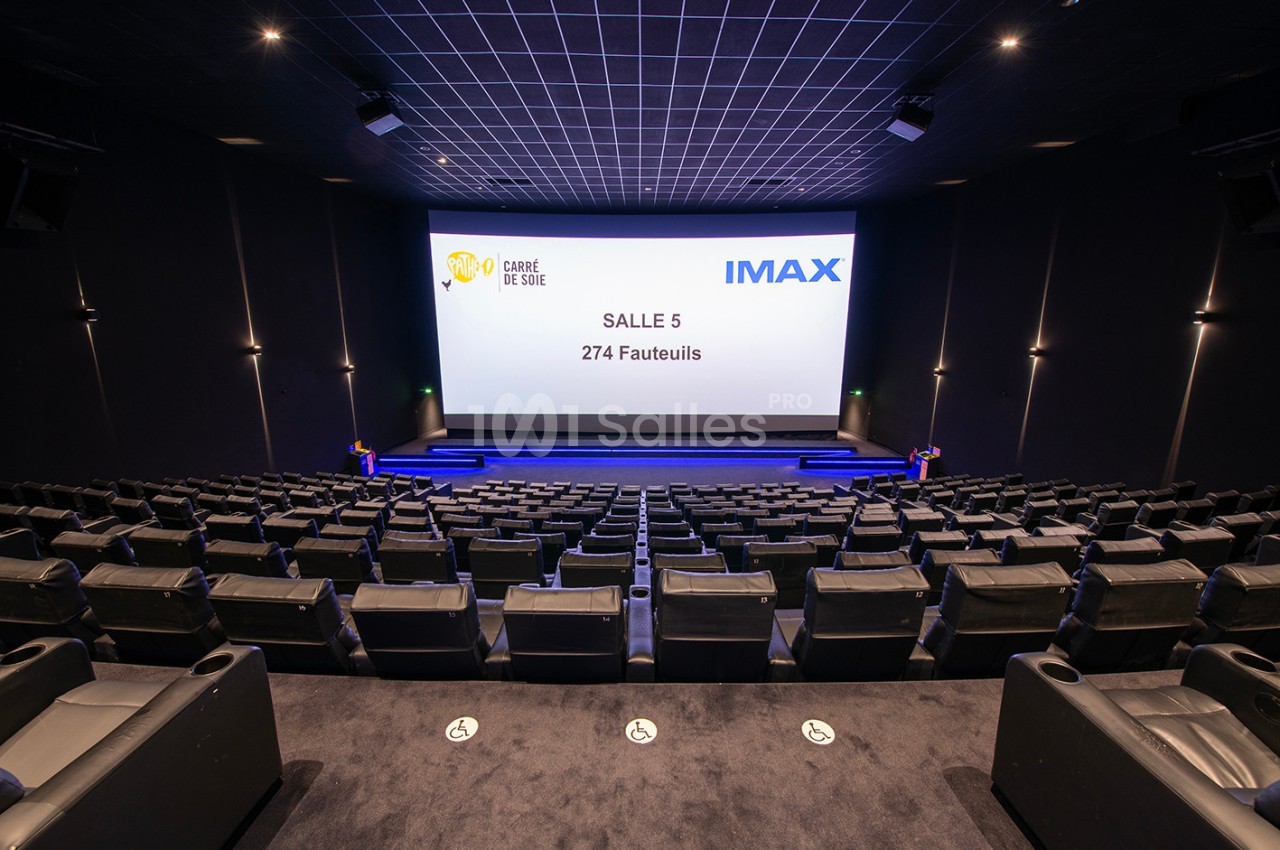 Salle de cinéma IMAX vide avec 274 fauteuils, écran géant et éclairage tamisé.