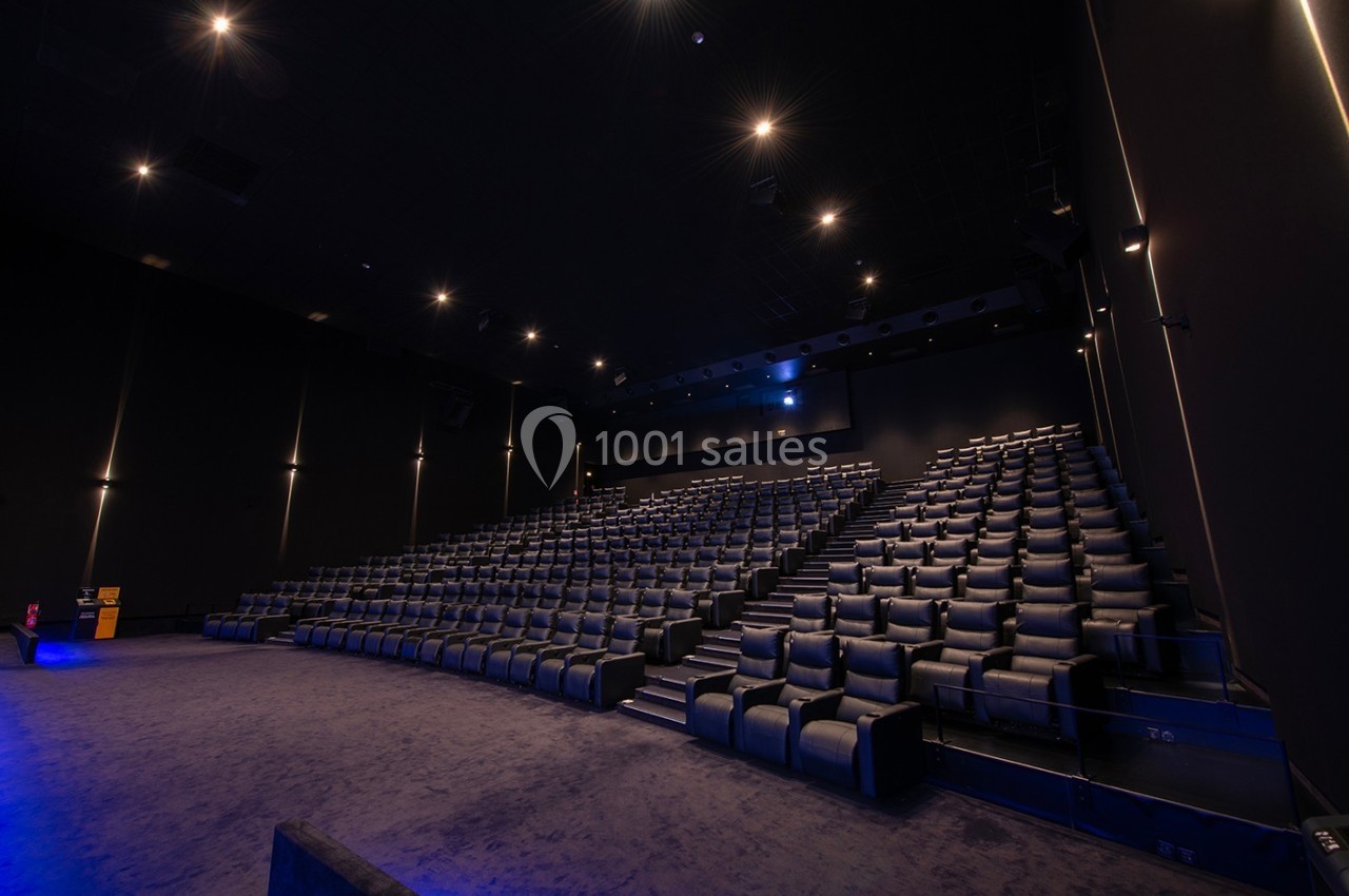 Salle de cinéma moderne avec rangées de sièges en cuir noir et éclairage tamisé.