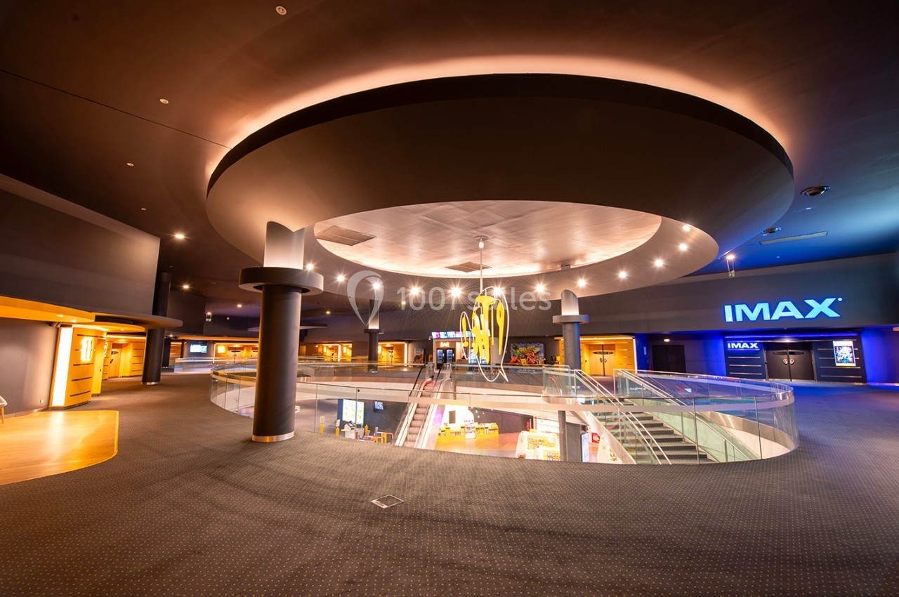 Hall d'entrée spacieux d'un cinéma avec escalier, éclairage moderne et enseigne IMAX visible au fond.