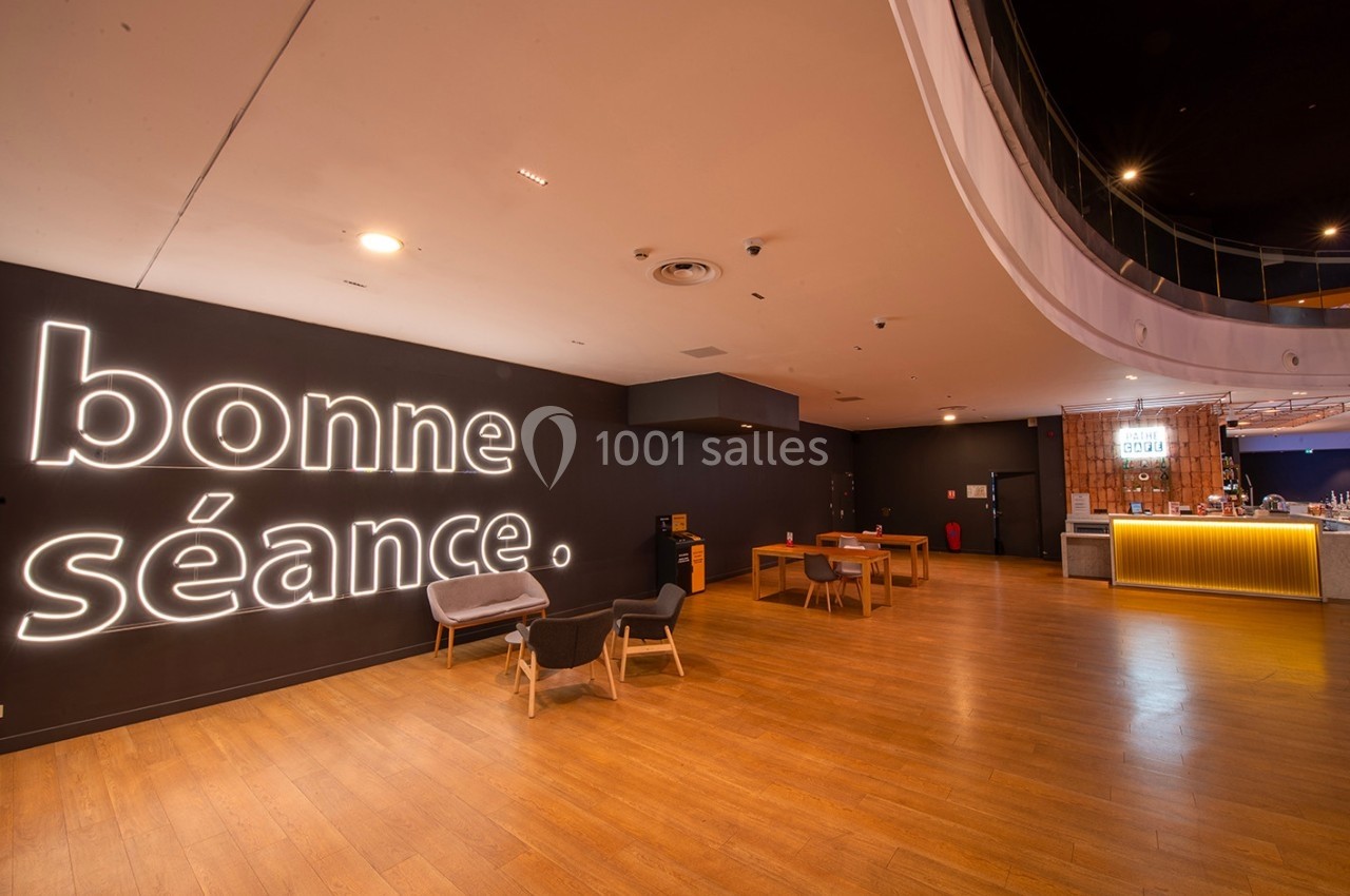 Espace d'accueil moderne avec sol en bois, mobilier minimaliste et inscription lumineuse ’bonne séance’ sur un mur sombre.