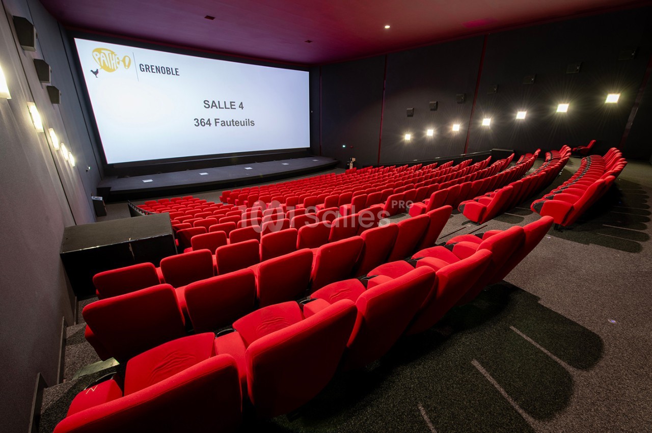 Salle de cinéma moderne avec des rangées de fauteuils rouges et un grand écran affichant ’Salle 4, 364 fauteuils’.