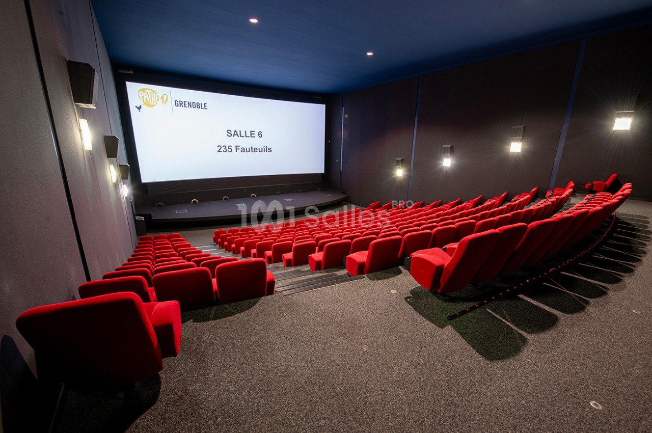 Salle de cinéma moderne avec des fauteuils rouges alignés et un écran affichant ’Salle 6, 235 fauteuils’.