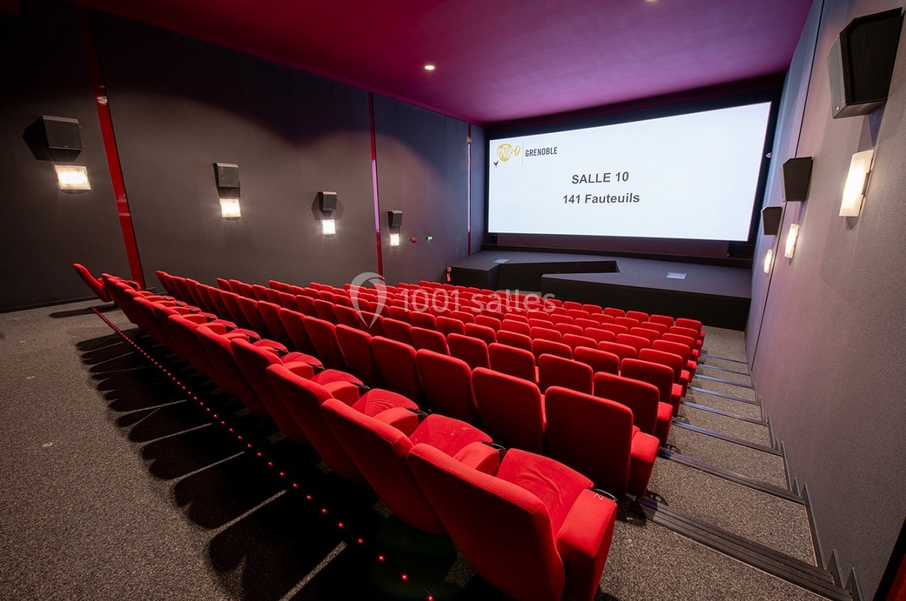 Salle de cinéma moderne avec rangées de fauteuils rouges et écran affichant ’Salle 10 - 141 fauteuils’.