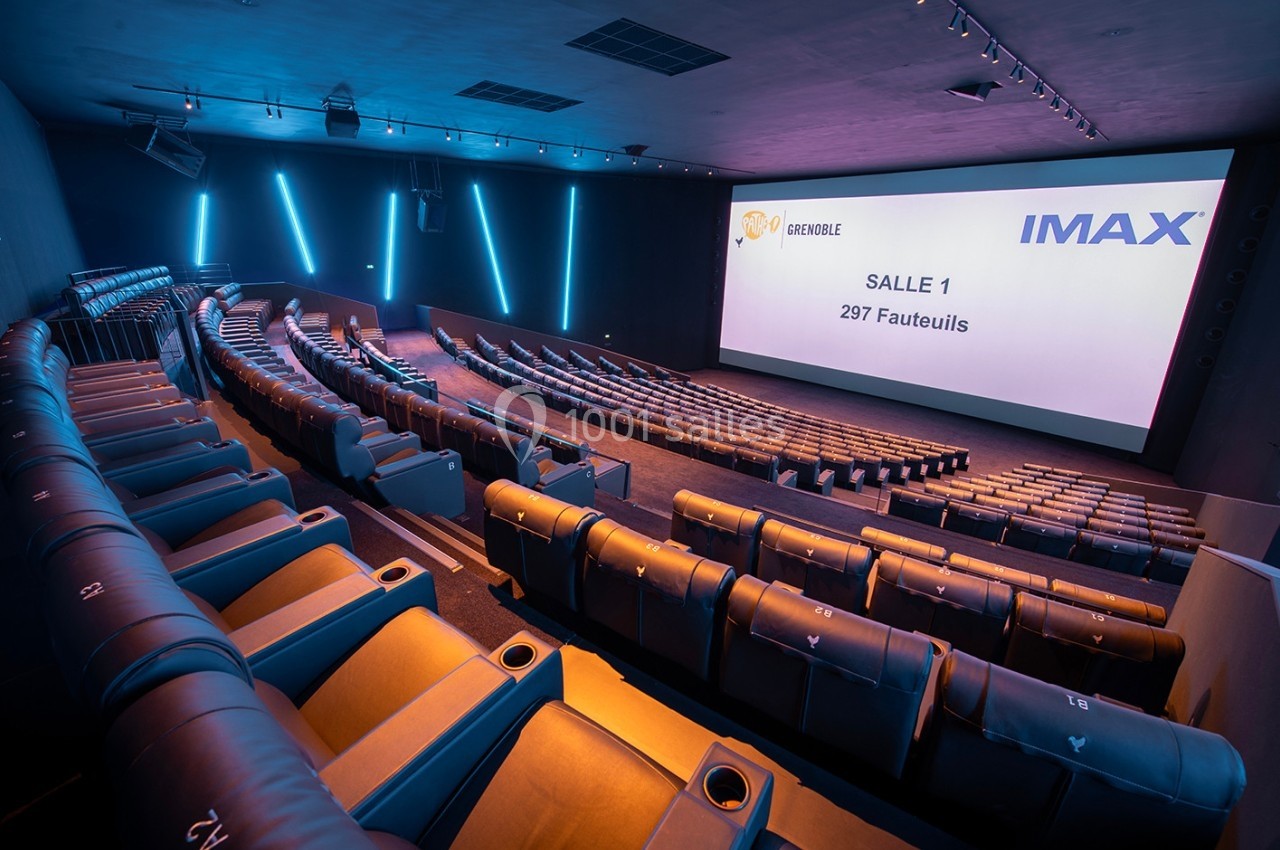 Salle de cinéma moderne avec sièges inclinables, écran IMAX et éclairage LED bleu sur les murs.
