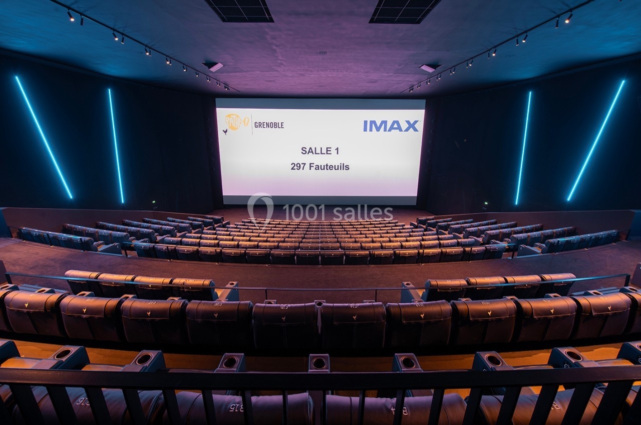 Salle de cinéma IMAX vide avec écran affichant ’Salle 1, 297 fauteuils’, rangées de sièges et éclairage moderne.