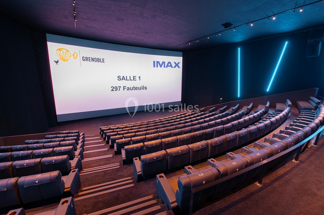 Salle de cinéma moderne avec écran géant, sièges en gradins et éclairage tamisé.
