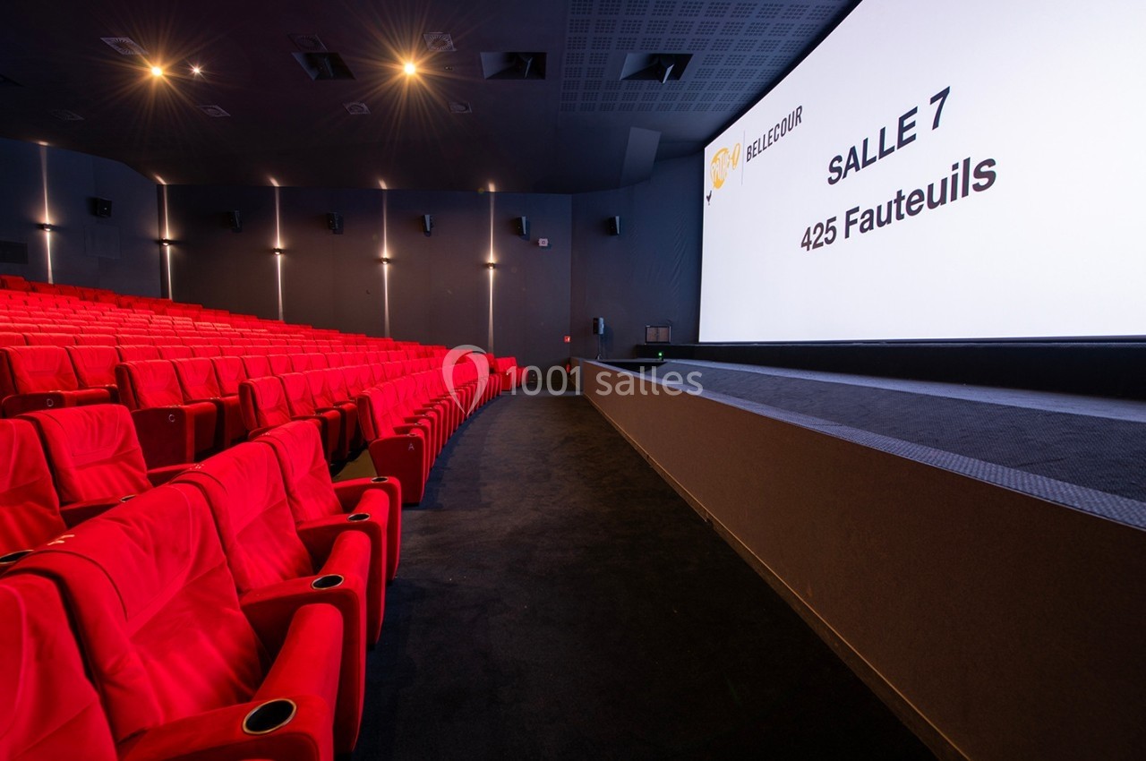 Salle de cinéma moderne avec rangées de fauteuils rouges et écran affichant ’Salle 7, 425 fauteuils’.