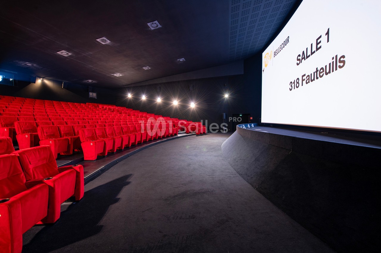 Salle de cinéma moderne avec des rangées de sièges rouges et un écran affichant ’Salle 1, 318 fauteuils’.