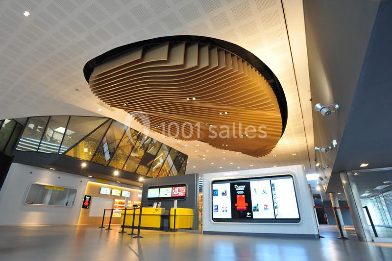 Plafond ondulé en bois dans un hall moderne avec guichets, écrans d'affichage et éclairage lumineux.