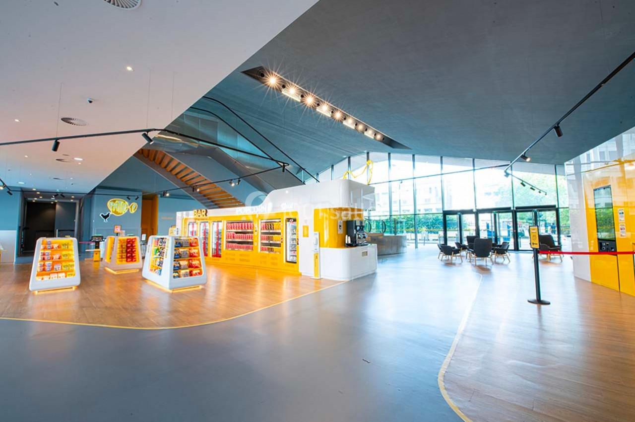 Intérieur lumineux d'un espace commercial moderne avec présentoirs colorés, comptoir et grandes baies vitrées.