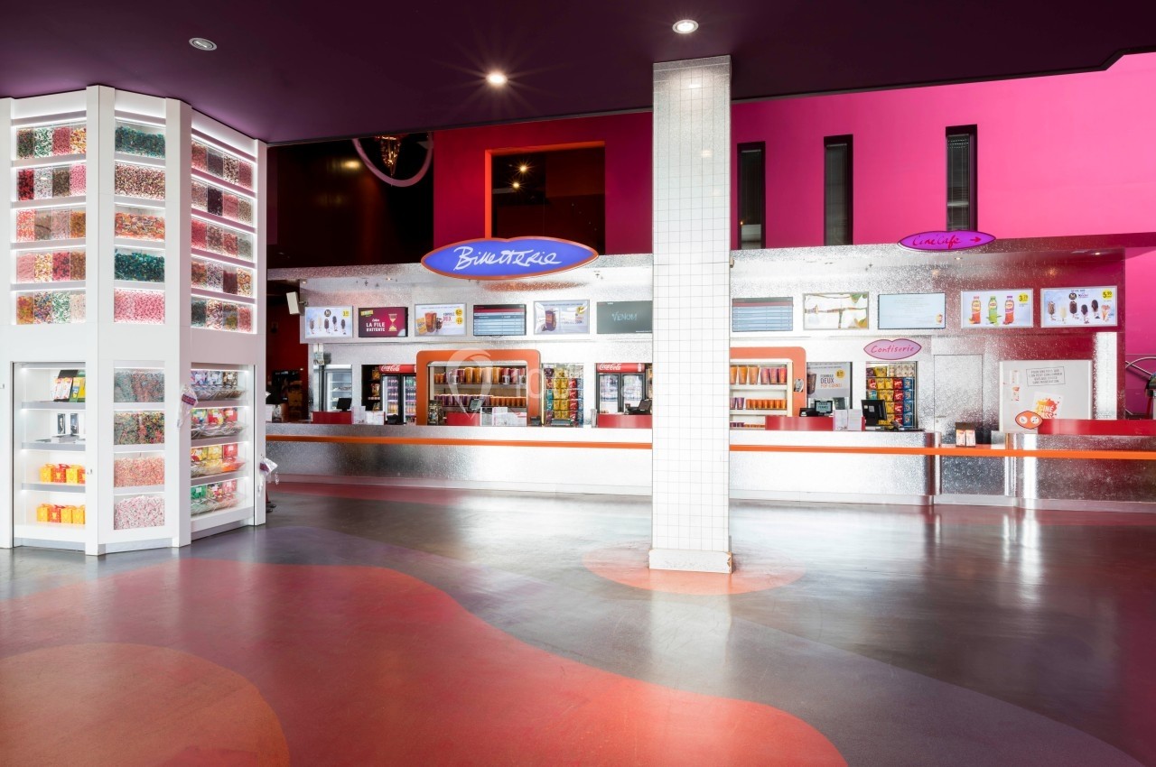 Comptoir de confiserie et boissons dans un cinéma avec présentoirs colorés et décorations modernes.