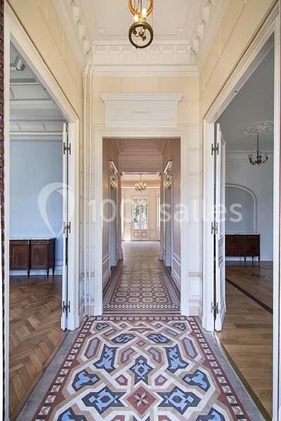 Vue d'un couloir lumineux avec sol en mosaïque, portes ouvertes et parquet dans les pièces adjacentes.
