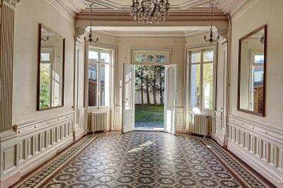 Cuisine vide avec carrelage beige, évier mural, étagères blanches, réfrigérateur et porte au fond.