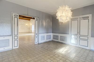 Cuisine vide avec carrelage beige, évier mural, étagères blanches, réfrigérateur et porte au fond.