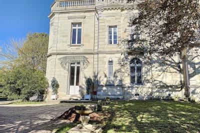 Cuisine vide avec carrelage beige, évier mural, étagères blanches, réfrigérateur et porte au fond.