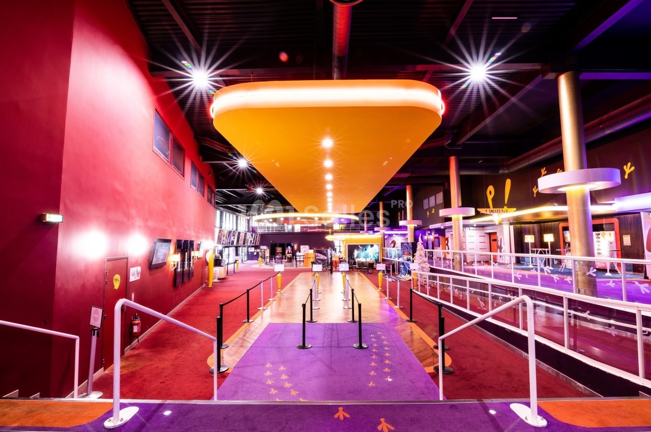 Hall d'entrée spacieux et coloré avec tapis violet, éclairage lumineux et barrières de guidage.