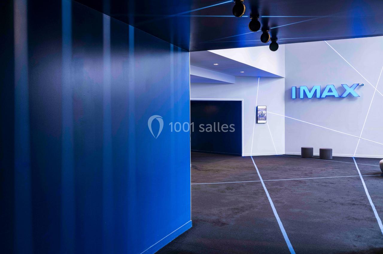 Entrée d'une salle IMAX avec murs bleus, sol sombre et éclairage moderne.