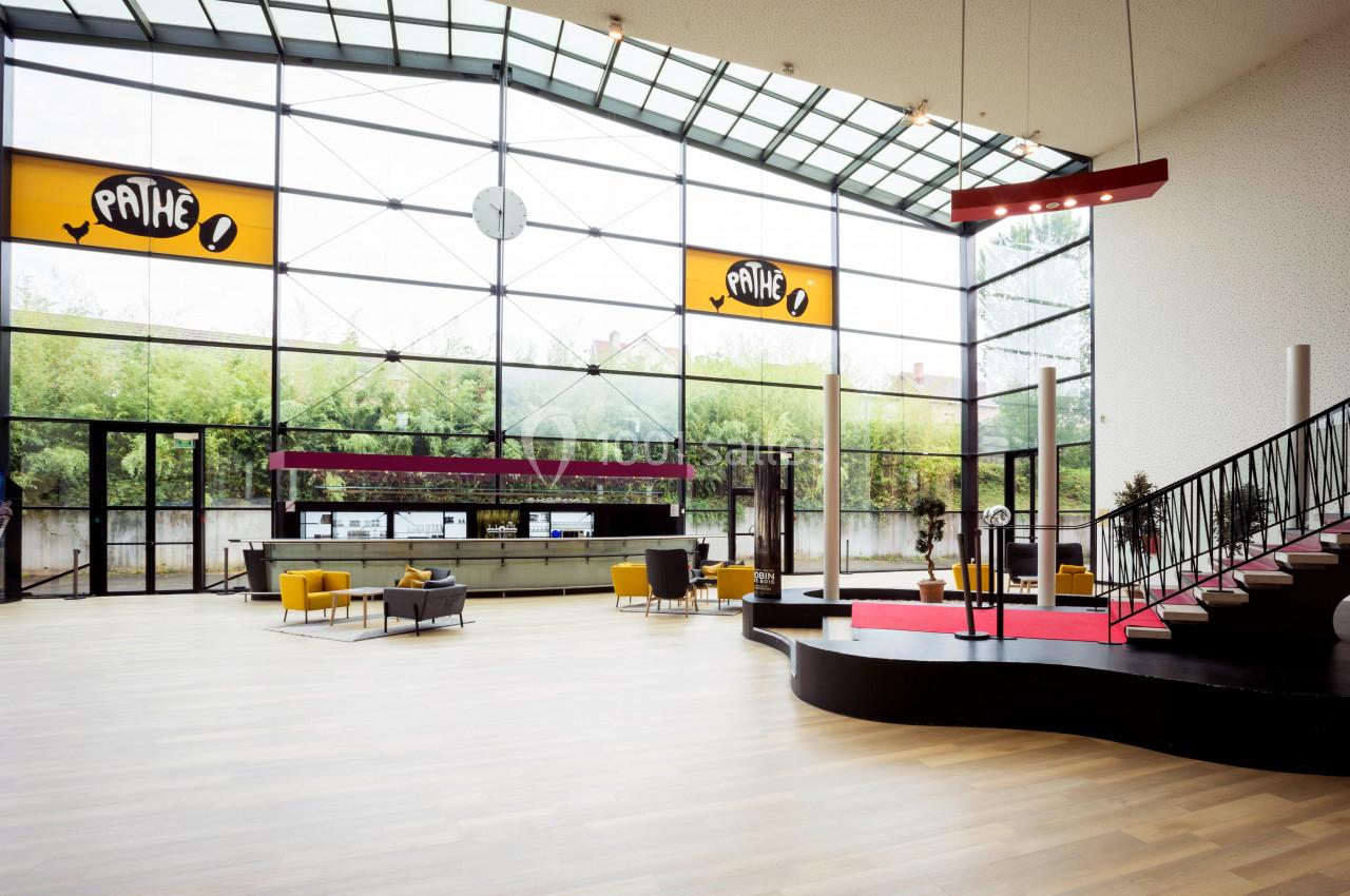 Location salle Liévin (Pas-de-Calais) - Pathé Liévin #3 Hall spacieux avec grandes baies vitrées, escalier moderne, mobilier jaune et comptoir d'accueil sous enseignes Pathé.