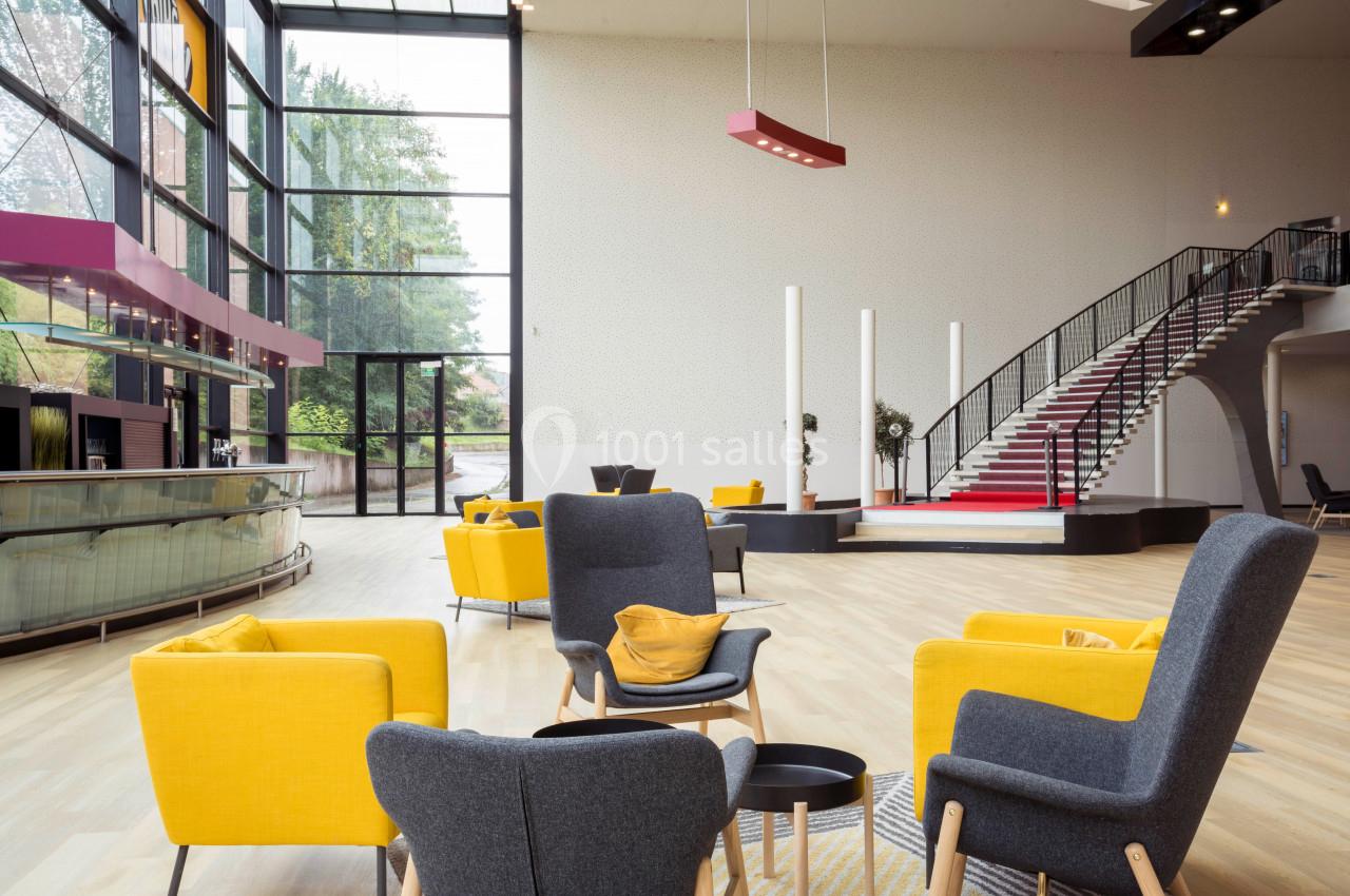 Location salle Liévin (Pas-de-Calais) - Pathé Liévin #5 Espace intérieur lumineux avec fauteuils jaunes et gris, escalier en colimaçon et grandes baies vitrées donnant sur l…
