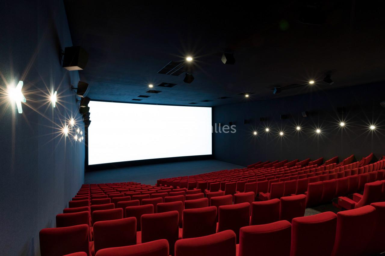 Location salle Liévin (Pas-de-Calais) - Pathé Liévin #7 Salle de cinéma vide avec des rangées de sièges rouges et un grand écran blanc allumé.