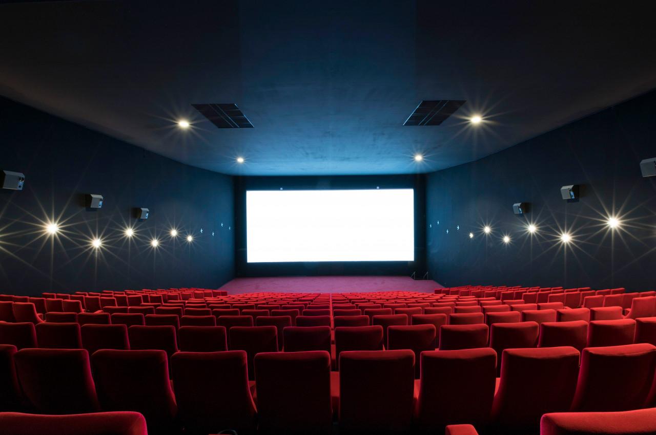Location salle Liévin (Pas-de-Calais) - Pathé Liévin #8 Salle de cinéma vide avec des rangées de sièges rouges et un grand écran blanc allumé au fond.