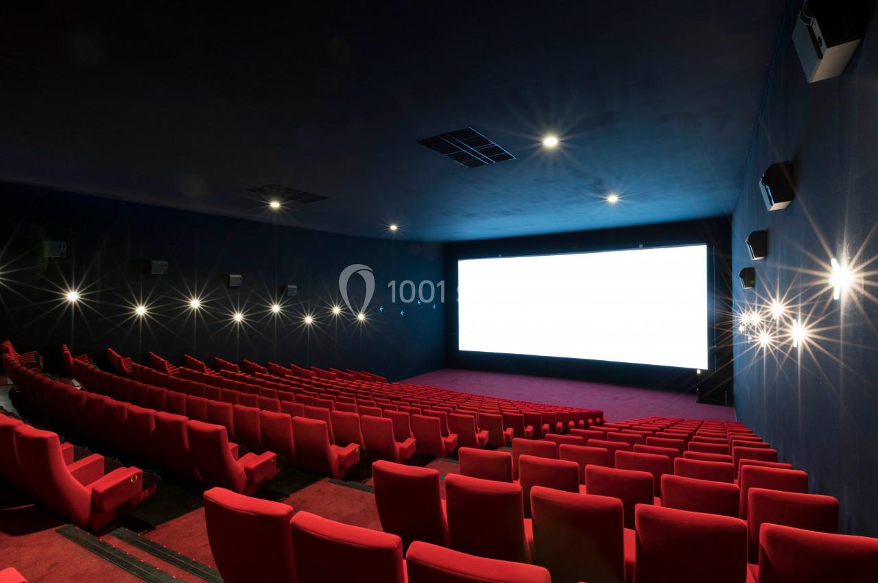Location salle Liévin (Pas-de-Calais) - Pathé Liévin #9 Salle de cinéma vide avec rangées de fauteuils rouges et un grand écran blanc allumé au fond.