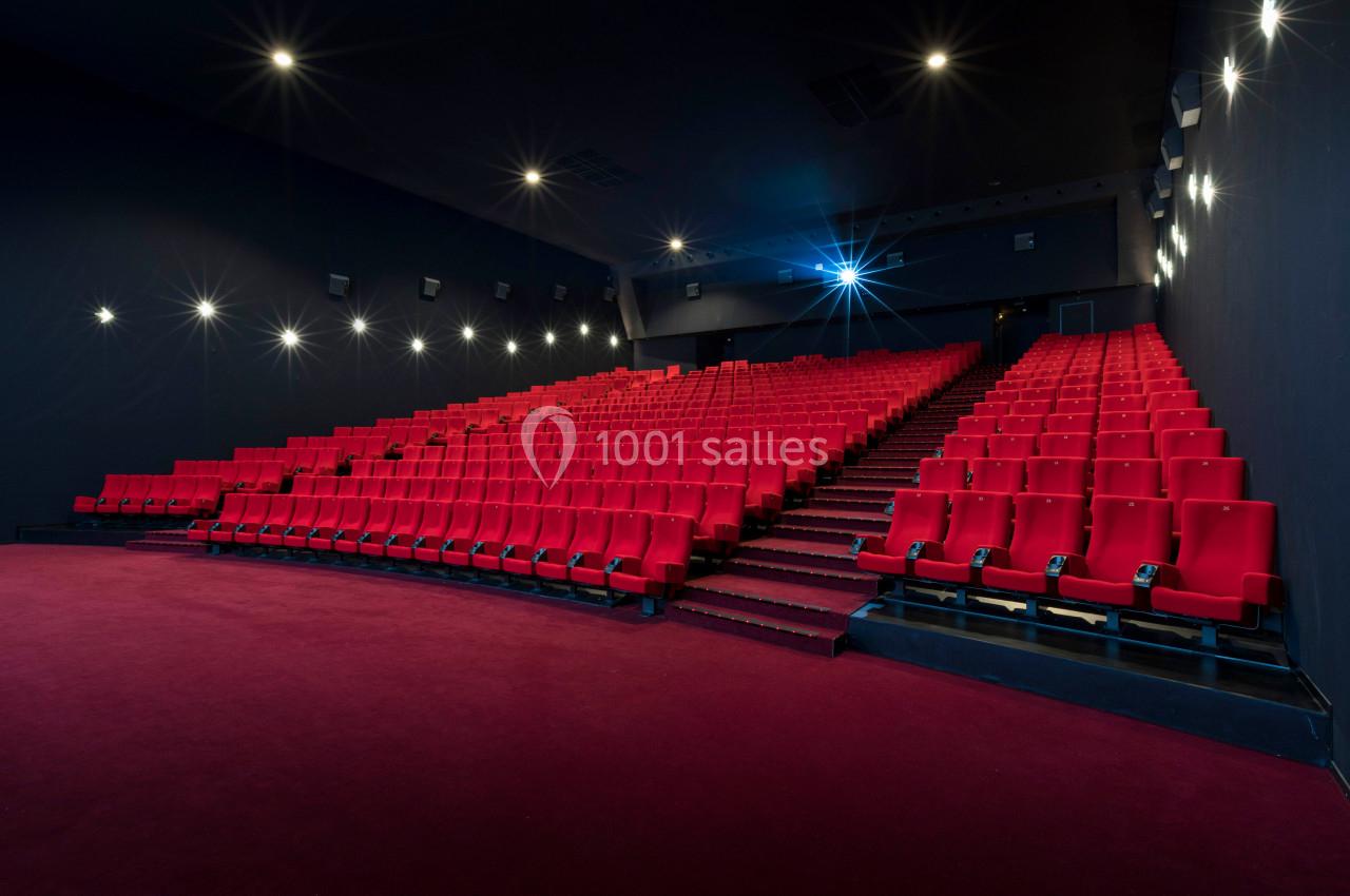Location salle Liévin (Pas-de-Calais) - Pathé Liévin #10 Salle de cinéma vide avec rangées de fauteuils rouges, éclairage tamisé et écran hors champ.