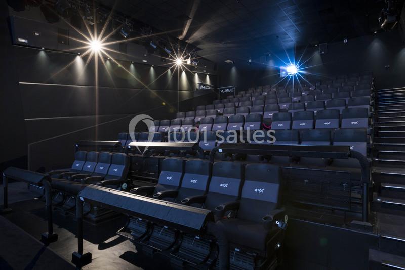 Salle de cinéma moderne avec sièges inclinables, éclairage tamisé et projecteur allumé.